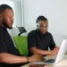 Young African professionals using digital financial tools on laptops